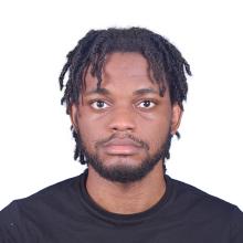 A young black man with a beard and short locs